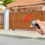 una persona punta un telecomando per aprire il cancello elettrico marrone sullo sfondo