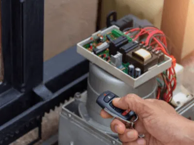qualcuno sta riparando il motore di un cancello automatico con un telecomando elettrico